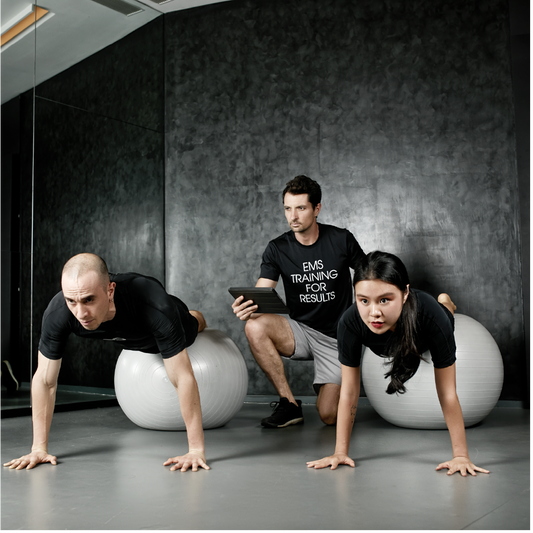 A fitness trainer helping a man and a woman do exercises using EMS technology